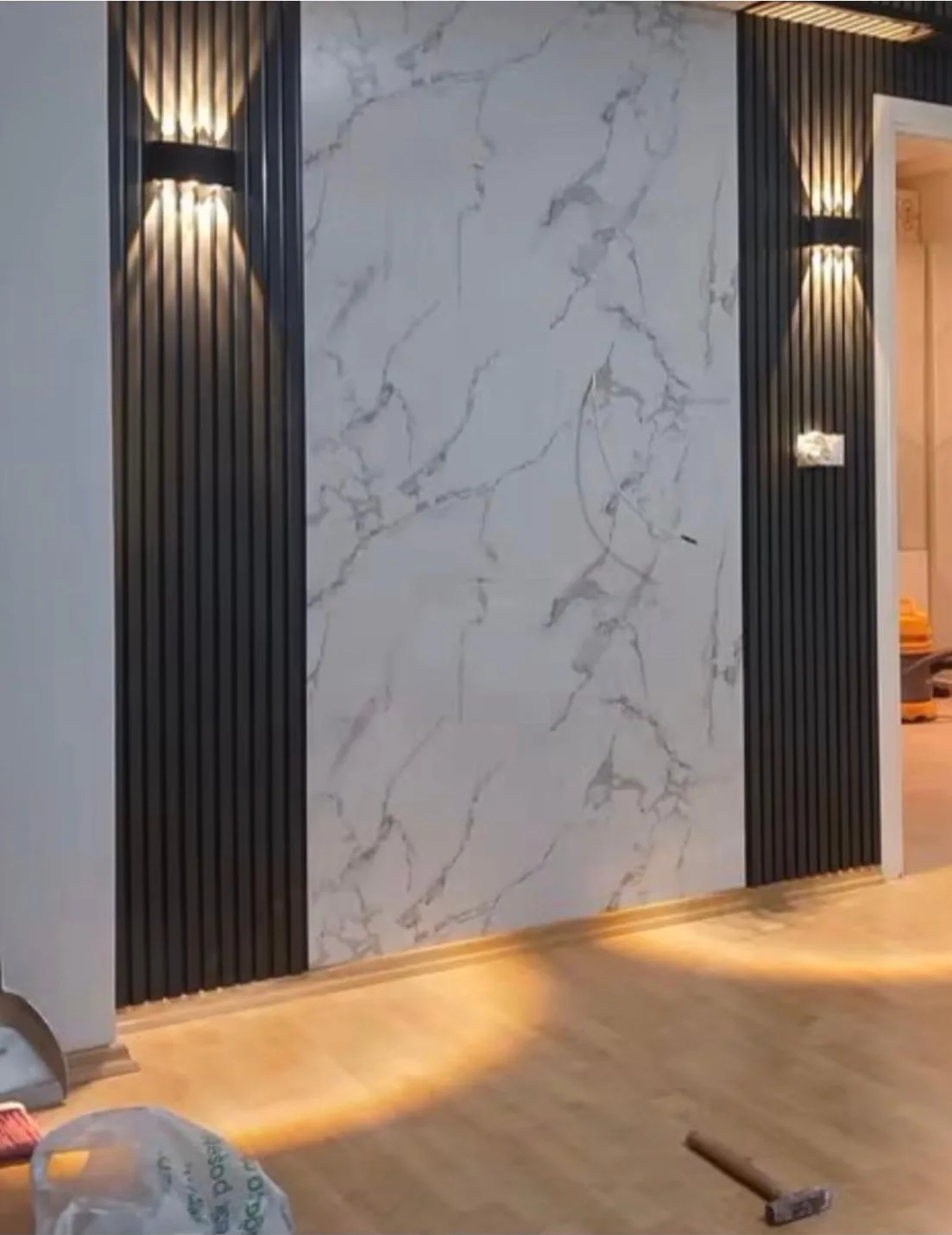 Feature wall in black fluted panel with a marble slab centre and paired uplights