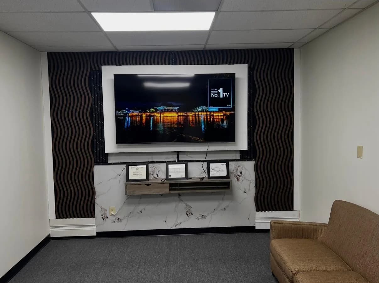 The finished media wall with black wave panelling, a porcelain slab ledge and a mounted display